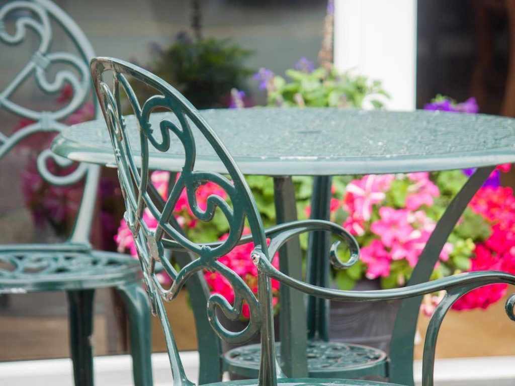 Green Garden Bistro Set Outside Against Colourful Flowers